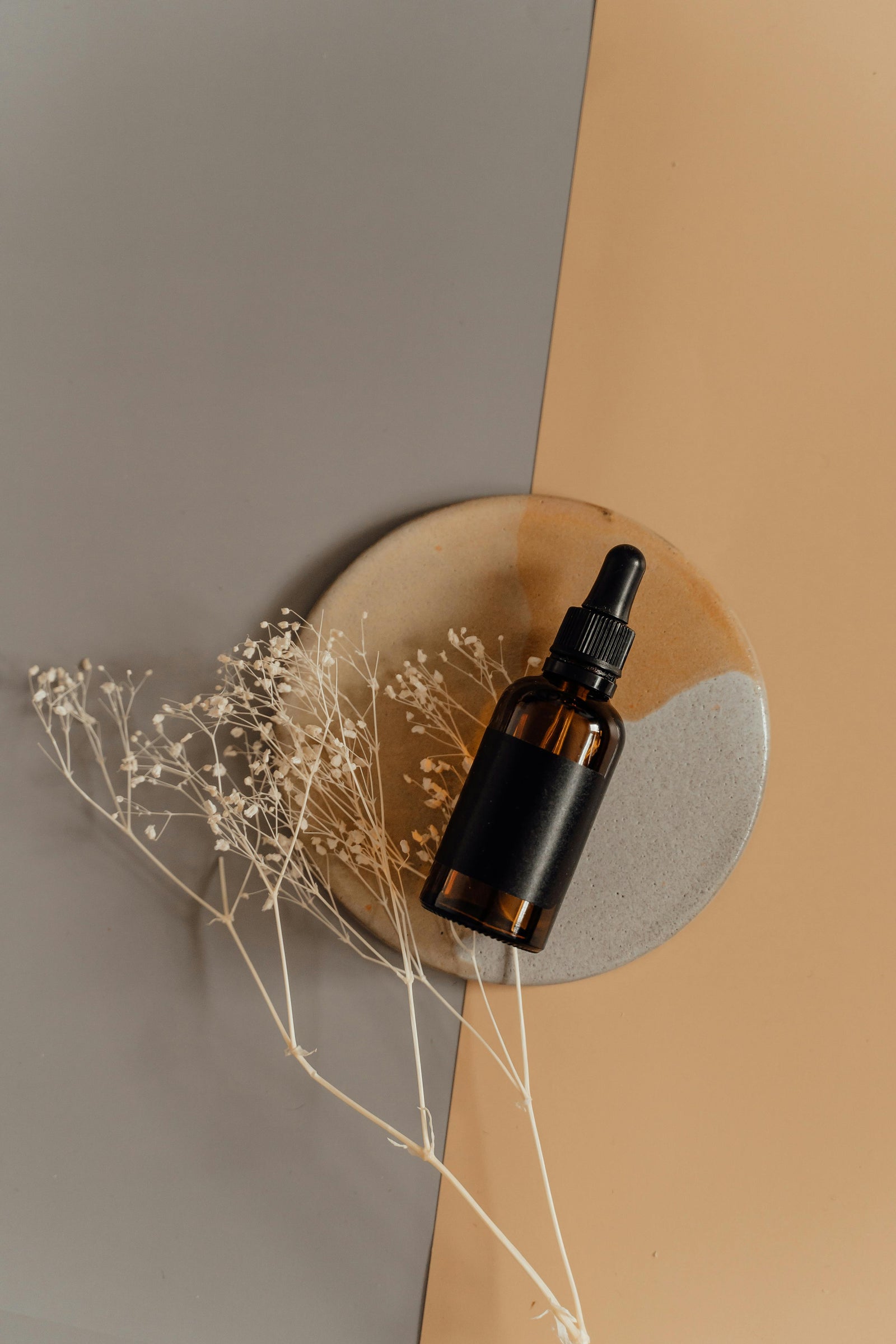 Pflegeserum mit getrockneten Blüten auf einer Steinschale
